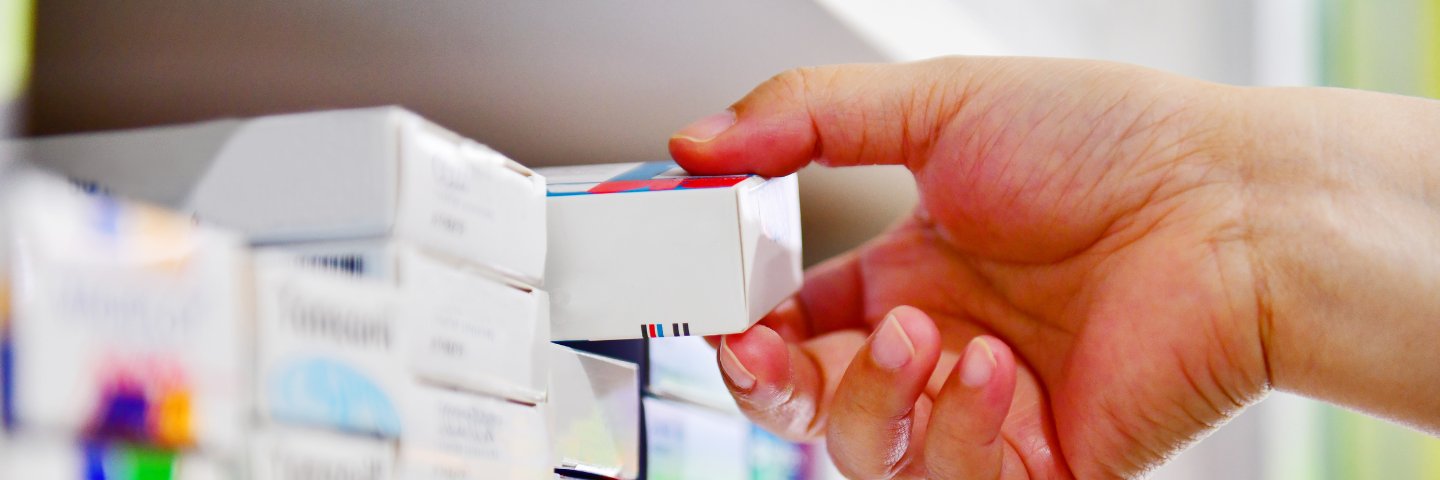 Hand taking medicine from a shelf