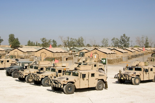 Humvees in desert camouflage at an army base.