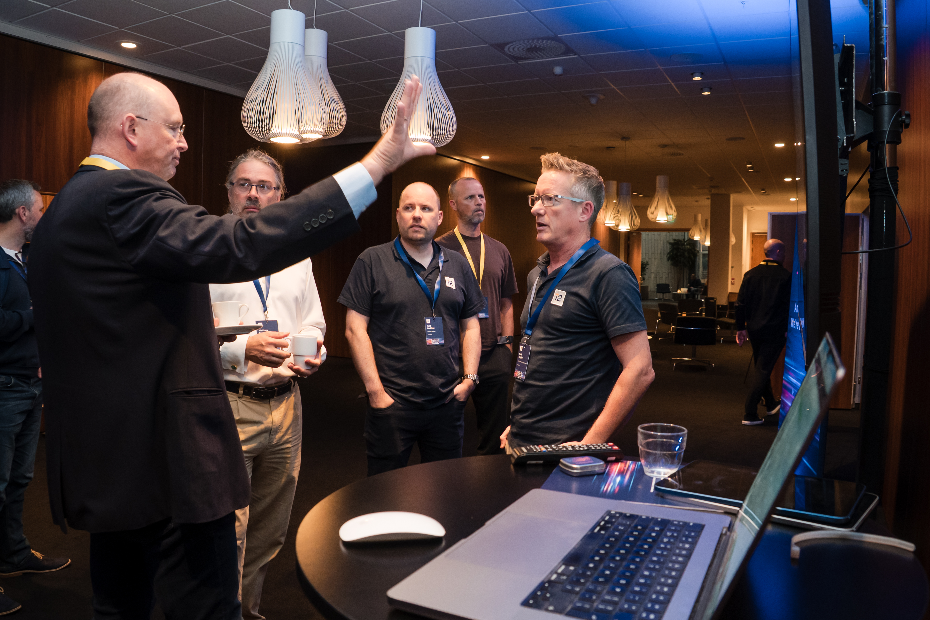Attendees in discussion around a demo laptop